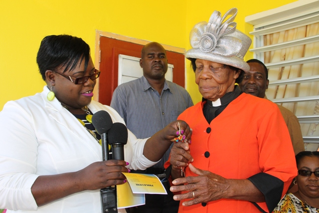 (L-R) Junior Minister of Social Development on Nevis Hon. Hazel Brandy-Williams handing over keys to a Pastor Eunice Griffin of her refurbished house on Pinney’s Road on March 10, 2017. Looking on are (l-r) Reverend Spencer Watts, her son David Griffin and (sitting) daughter-in-law Valencia Griffin
